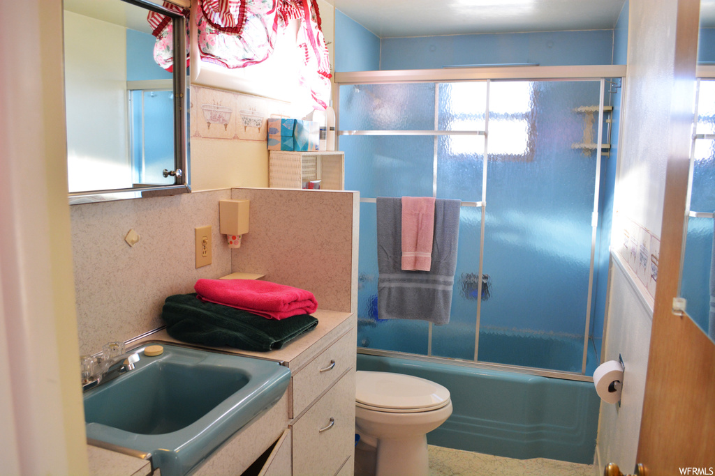 Full bathroom featuring enclosed tub / shower combo, large vanity, and toilet