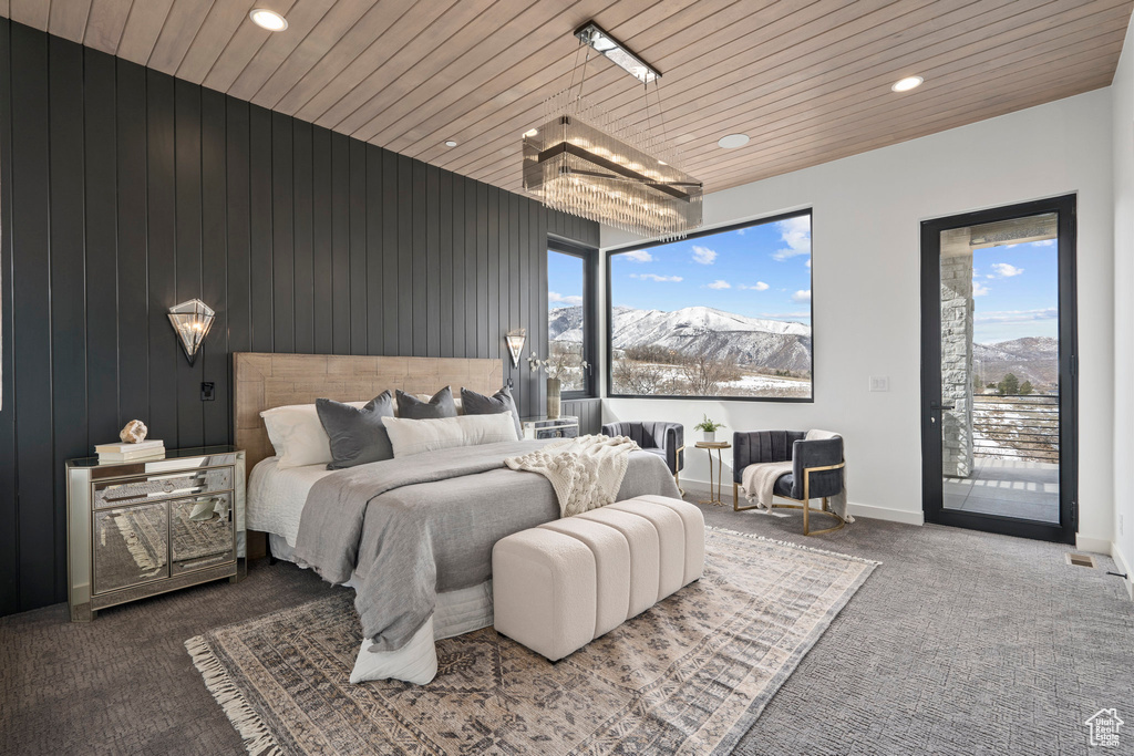 Bedroom featuring a mountain view, wood ceiling, multiple windows, and access to exterior