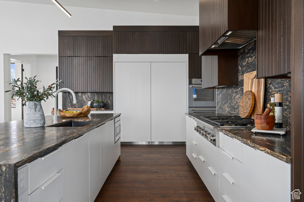 Kitchen featuring premium range hood, appliances with stainless steel finishes, dark stone counters, and tasteful backsplash