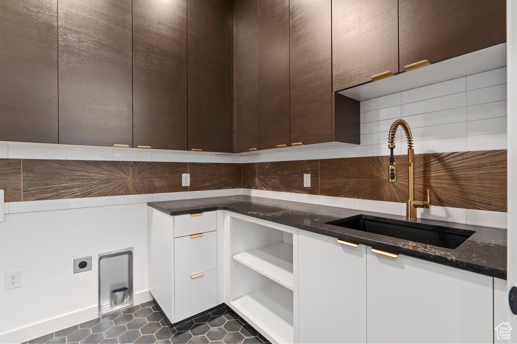 Kitchen with white cabinets, sink, dark stone countertops, and dark tile flooring
