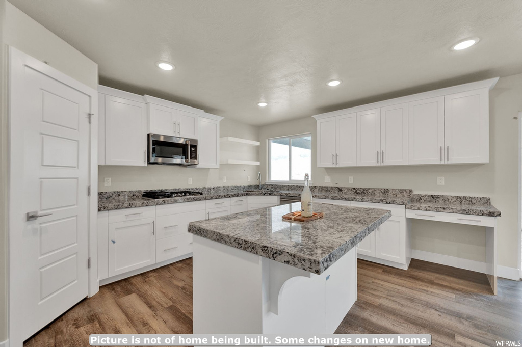 Kitchen featuring a center island, wood-type flooring, stainless steel appliances, and white cabinets