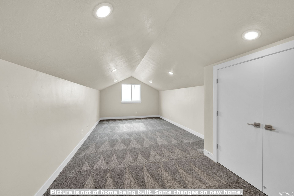 Additional living space featuring vaulted ceiling and dark colored carpet