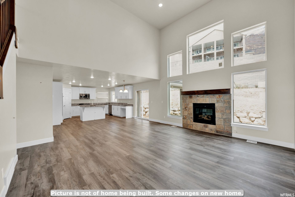 Unfurnished living room with a high ceiling, a fireplace, and dark hardwood / wood-style floors