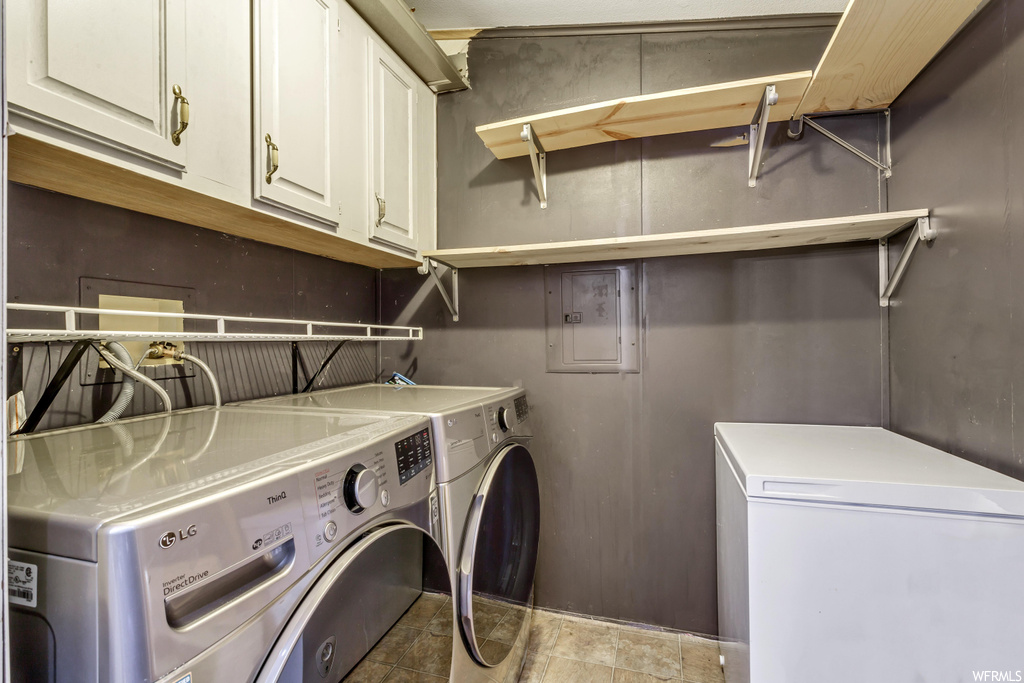 Laundry area featuring hookup for a washing machine, washer and clothes dryer, light tile floors, and cabinets