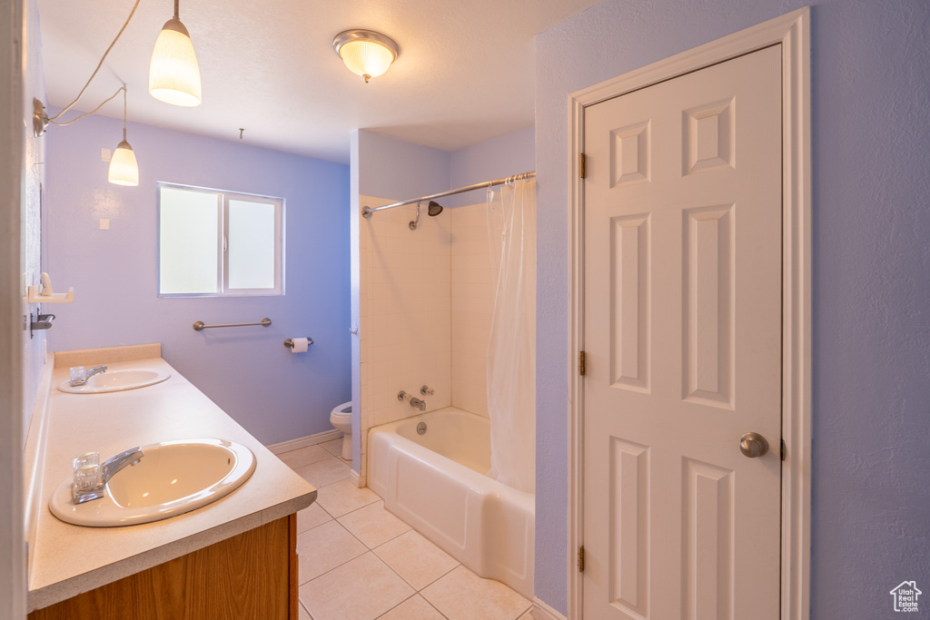 Bathroom featuring tile patterned flooring, toilet, double vanity, and shower / bath combination with curtain