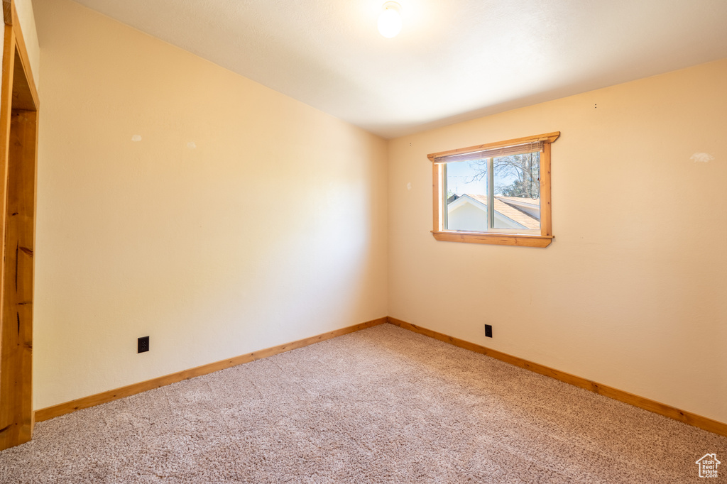Empty room with light colored carpet and baseboards