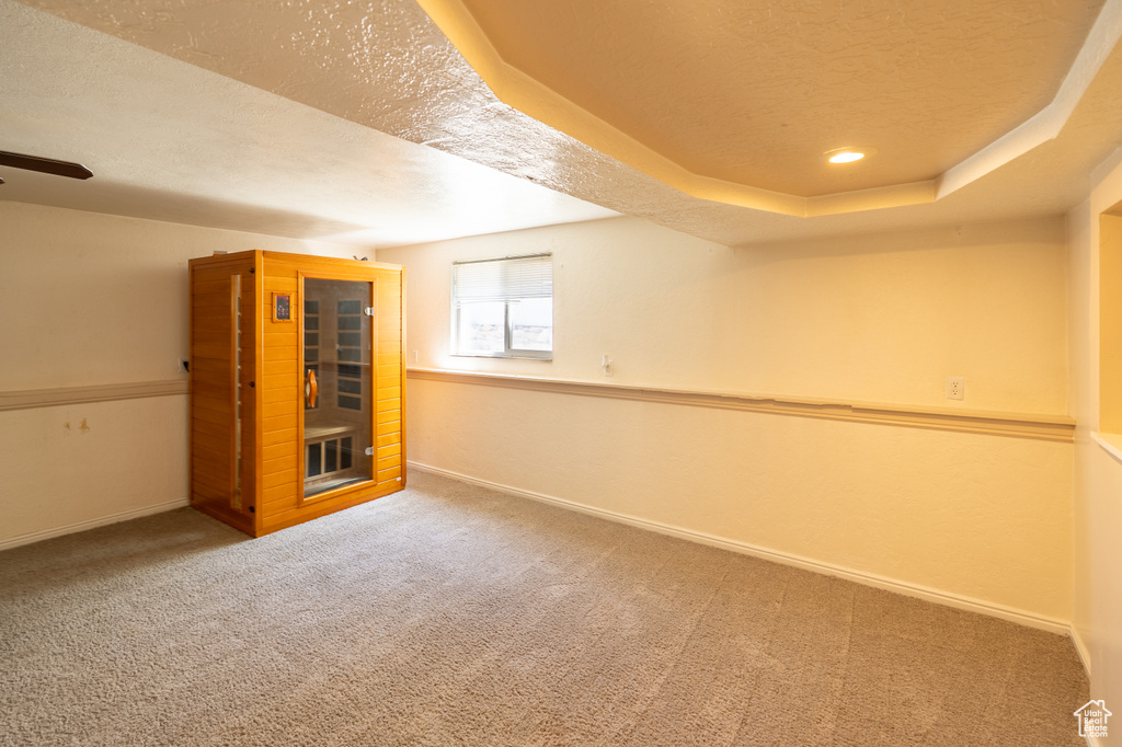 Basement with a textured ceiling, carpet floors, baseboards, and a ceiling fan