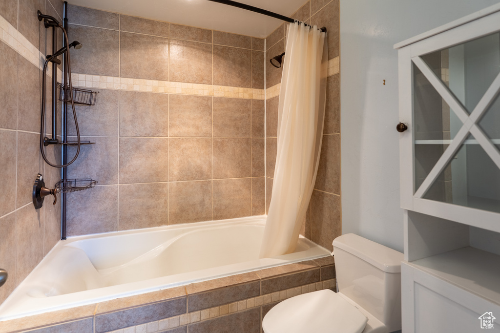Bathroom with tiled shower / bath and toilet