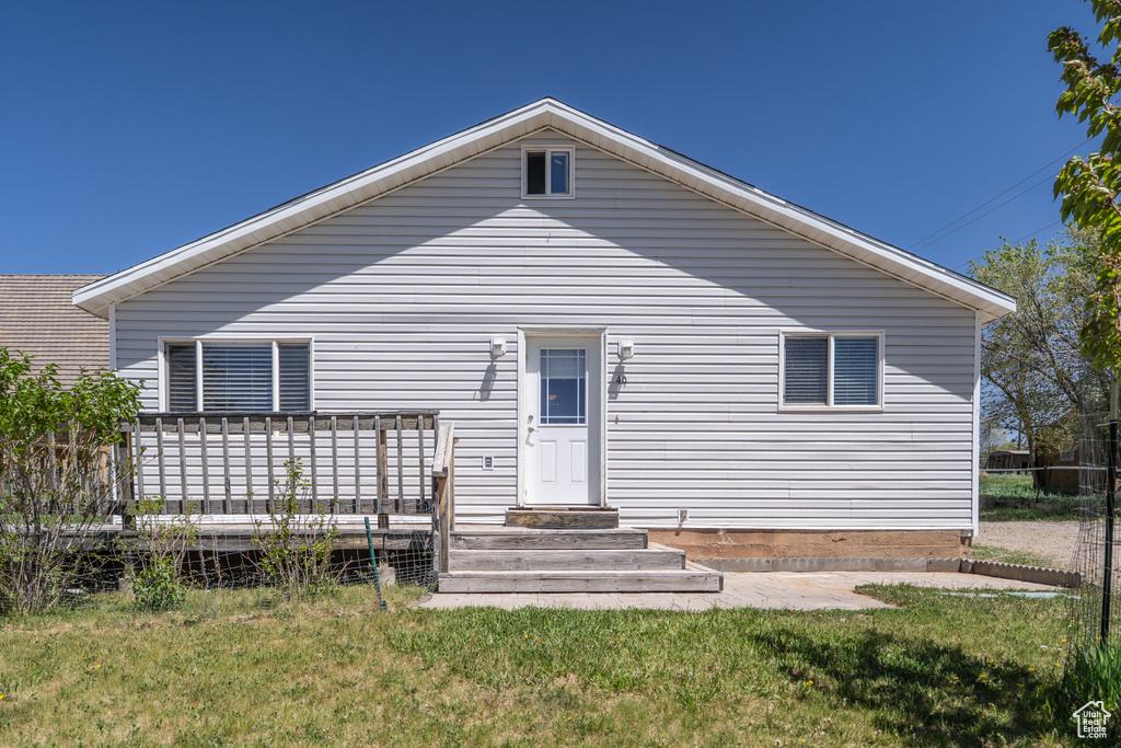 Back of house featuring a wooden deck and a lawn
