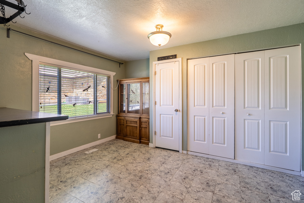Unfurnished bedroom with a textured ceiling, baseboards, and a closet