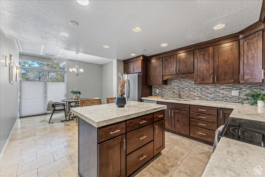 Kitchen featuring a chandelier, a textured ceiling, stainless steel refrigerator, and decorative light fixtures