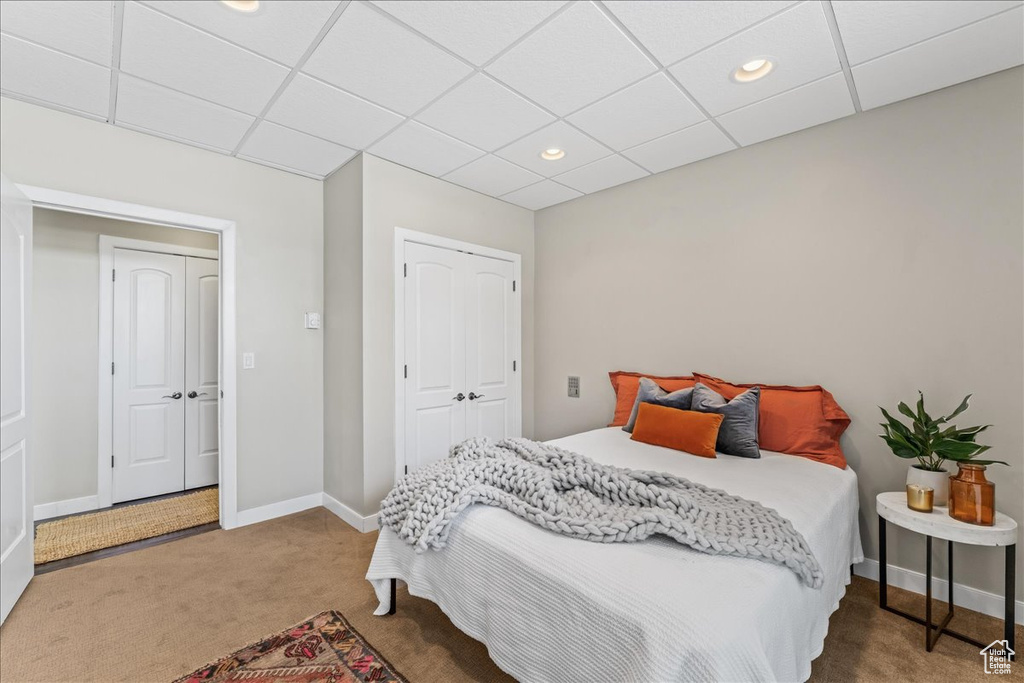 Bedroom with carpet flooring, a paneled ceiling, and a closet