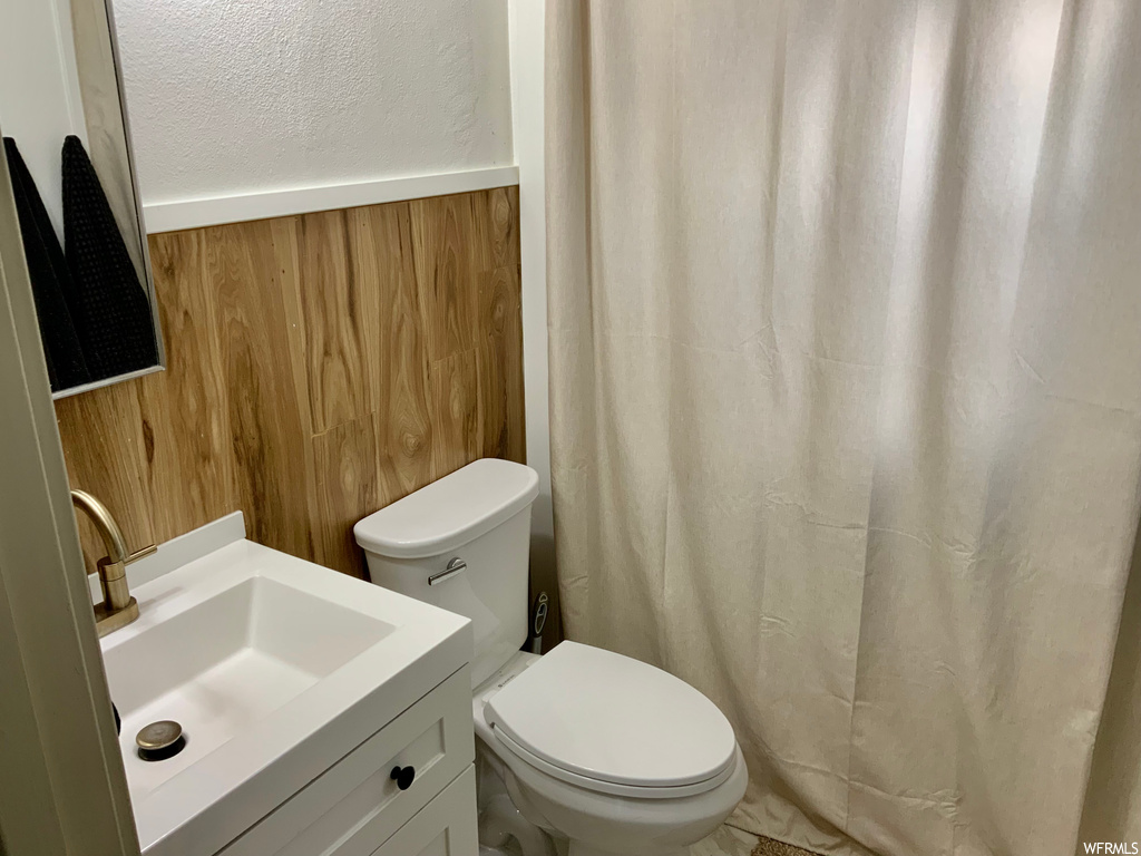 Bathroom with wood walls, toilet, and vanity
