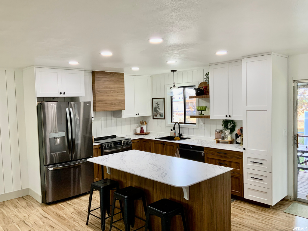 Kitchen with backsplash, stainless steel refrigerator with ice dispenser, white cabinets, and a kitchen island