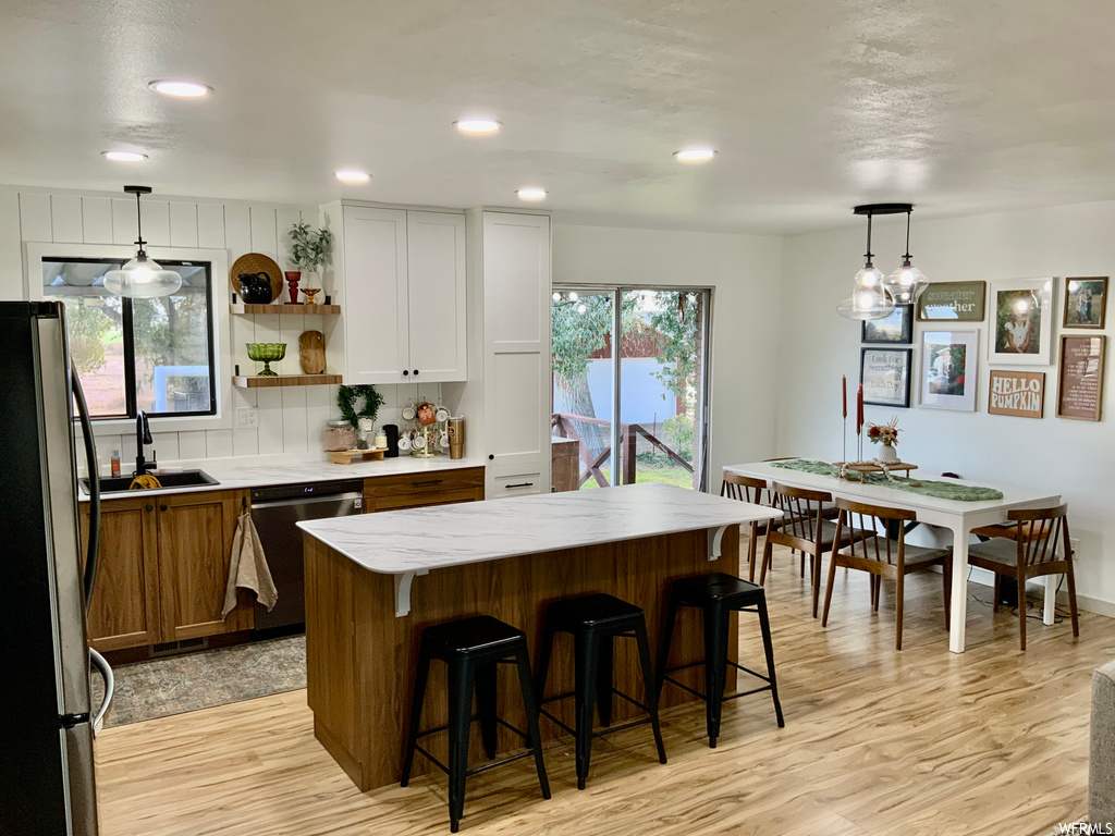 Kitchen with stainless steel appliances, hanging light fixtures, a center island, and white cabinets