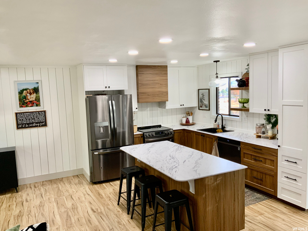Kitchen with sink, hanging light fixtures, black dishwasher, white cabinetry, and stainless steel fridge