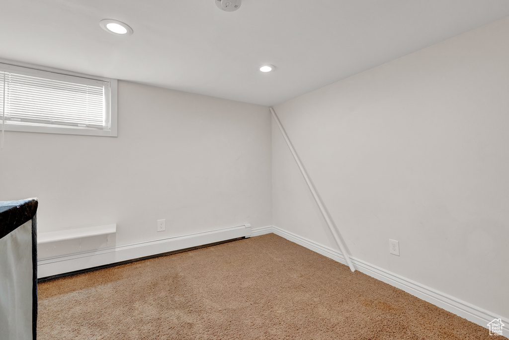Empty room with light carpet and baseboard heating