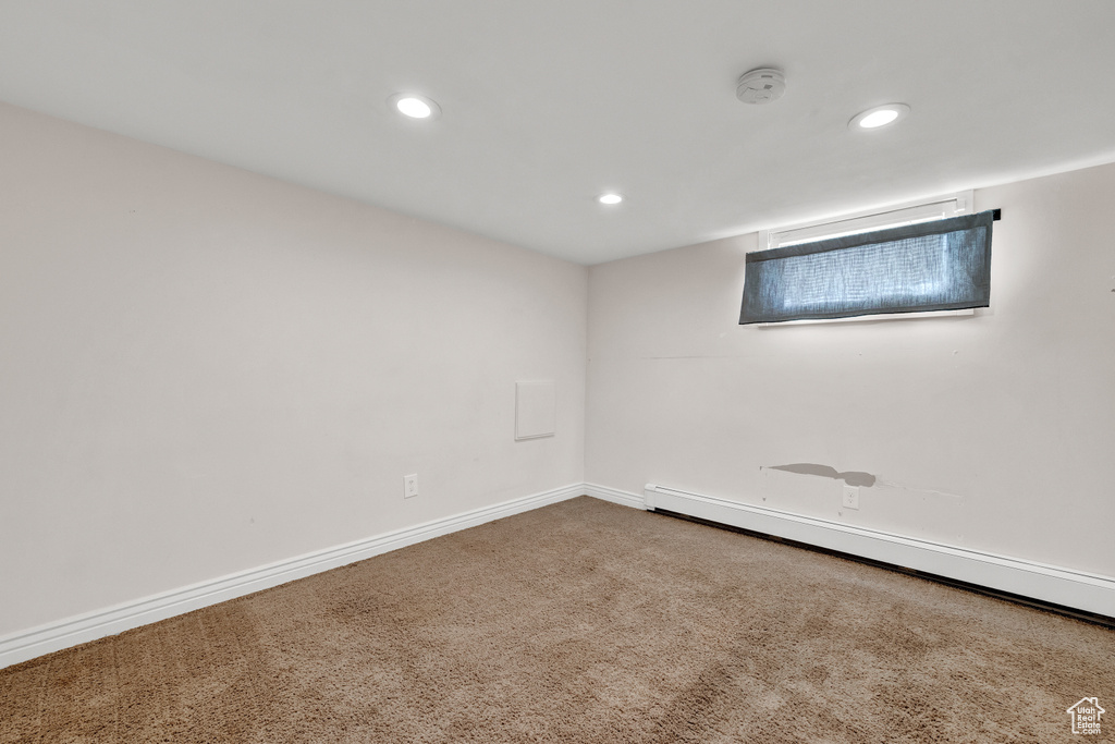 Carpeted spare room with baseboard heating