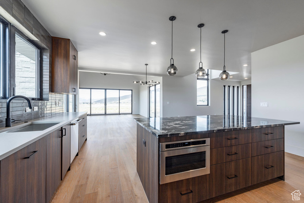 Kitchen featuring sink, light hardwood / wood-style floors, backsplash, and appliances with stainless steel finishes