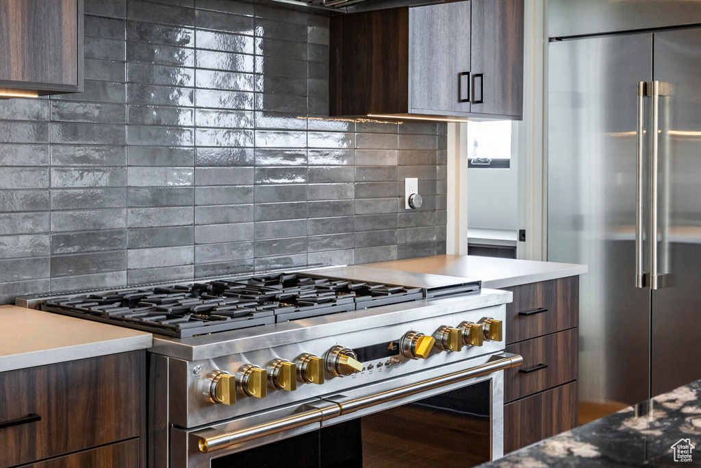 Kitchen with dark brown cabinets, tasteful backsplash, and high end appliances