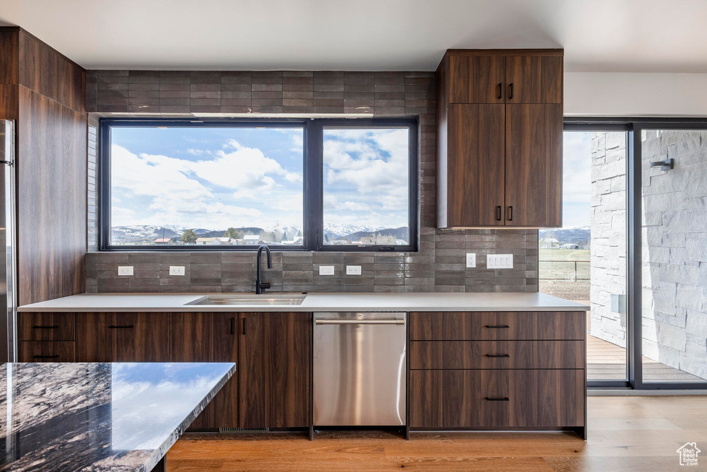 Kitchen featuring stainless steel dishwasher, tasteful backsplash, light wood-type flooring, and a wealth of natural light