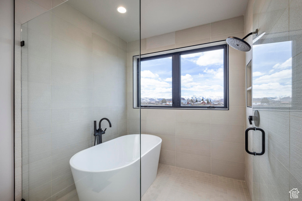 Bathroom featuring tile walls and independent shower and bath
