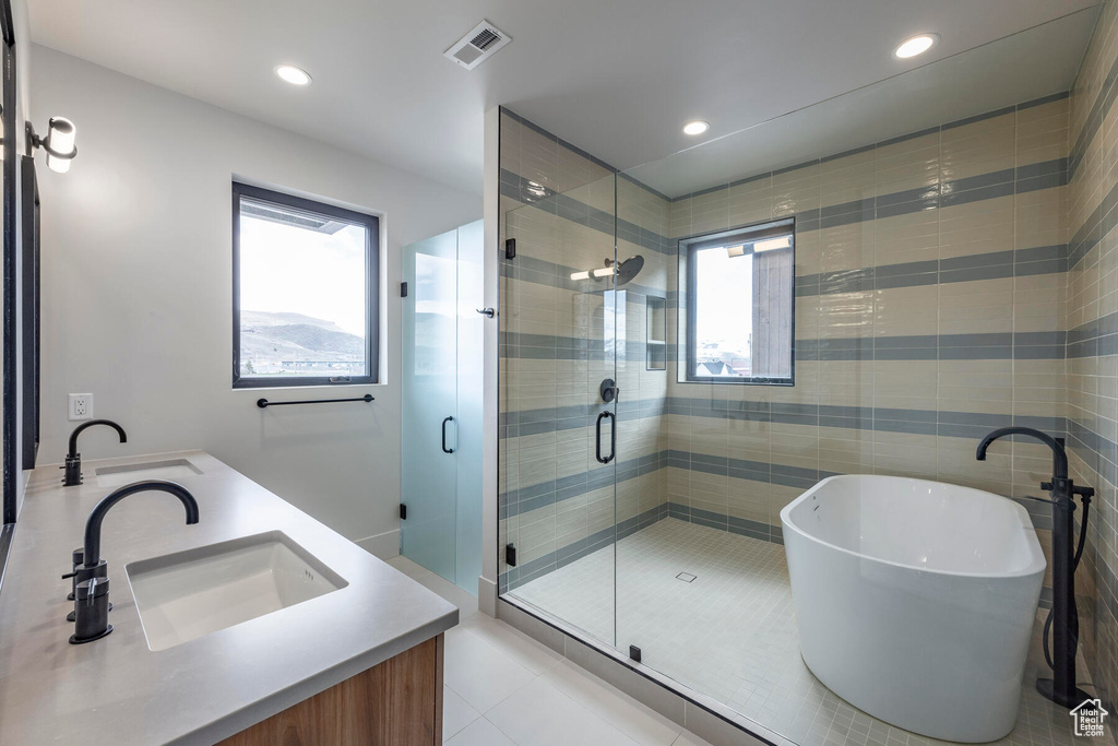 Bathroom featuring double vanity, shower with separate bathtub, and tile flooring
