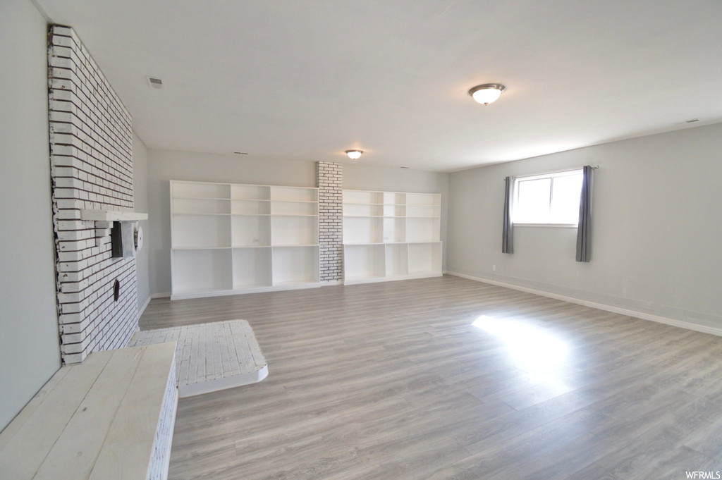 Unfurnished living room featuring light hardwood / wood-style floors, a fireplace, and built in features