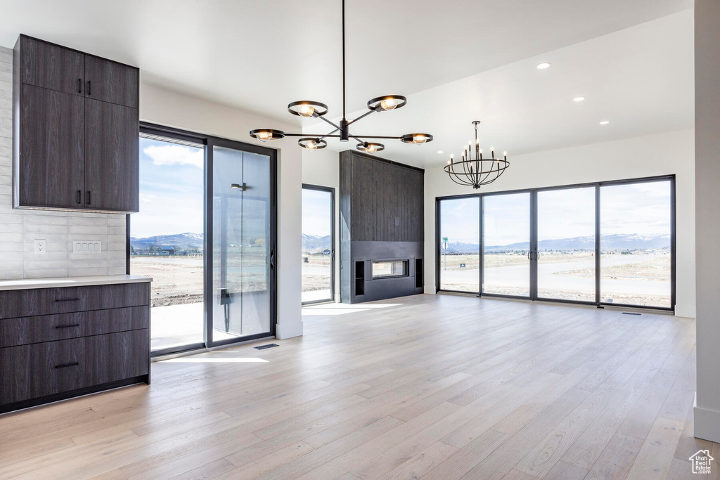 Unfurnished living room featuring a mountain view, a fireplace, plenty of natural light, and light hardwood / wood-style flooring