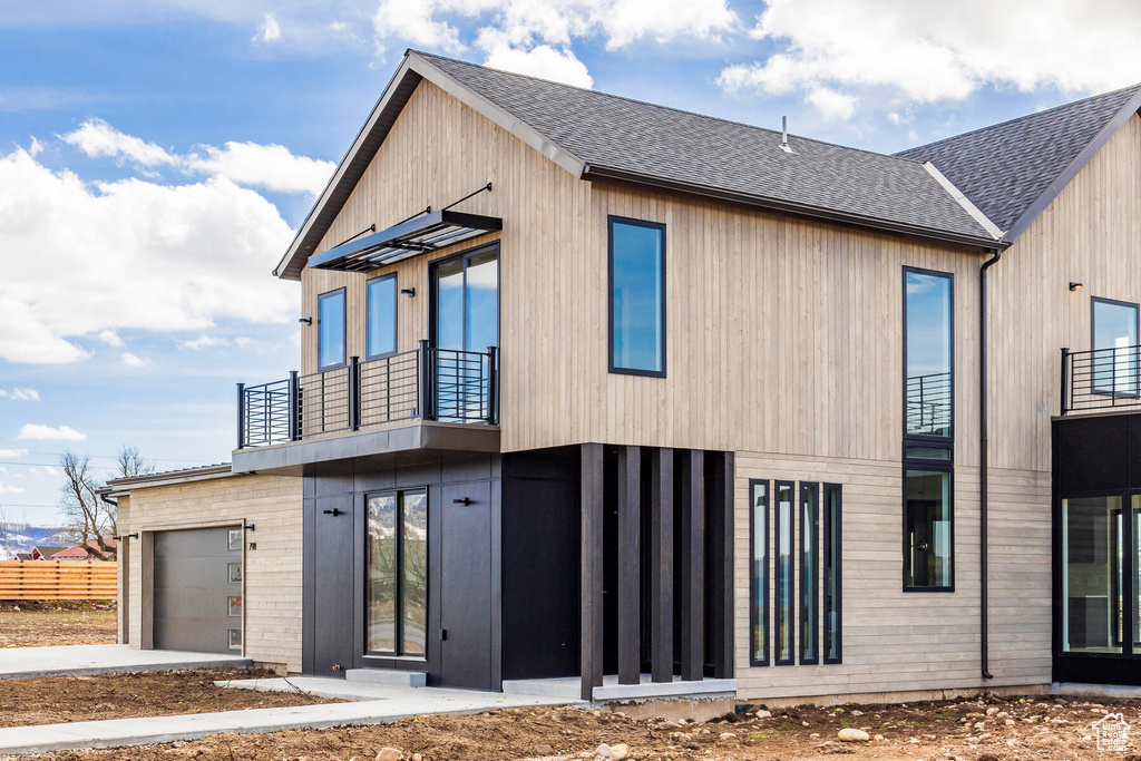 Back of house featuring a garage and a balcony