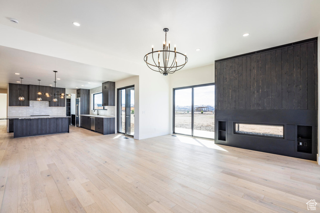 Unfurnished living room with light hardwood / wood-style floors and a chandelier