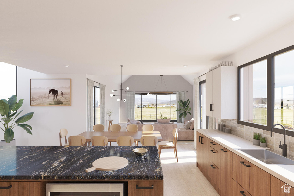 Kitchen featuring light hardwood / wood-style floors, decorative backsplash, sink, a chandelier, and a kitchen island