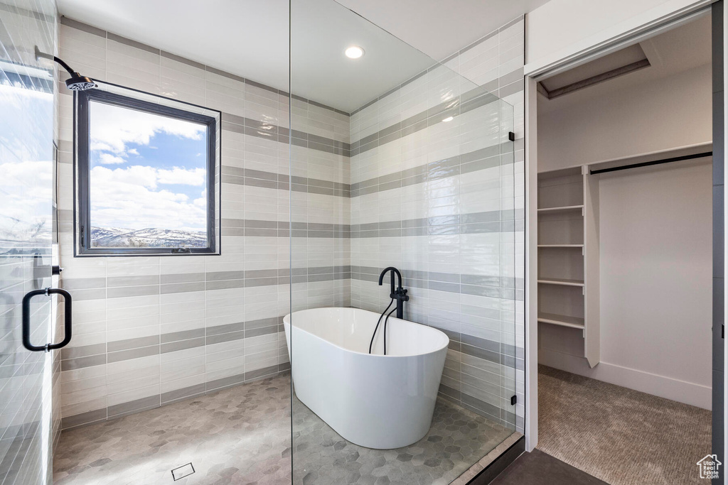 Bathroom featuring tile walls and shower with separate bathtub