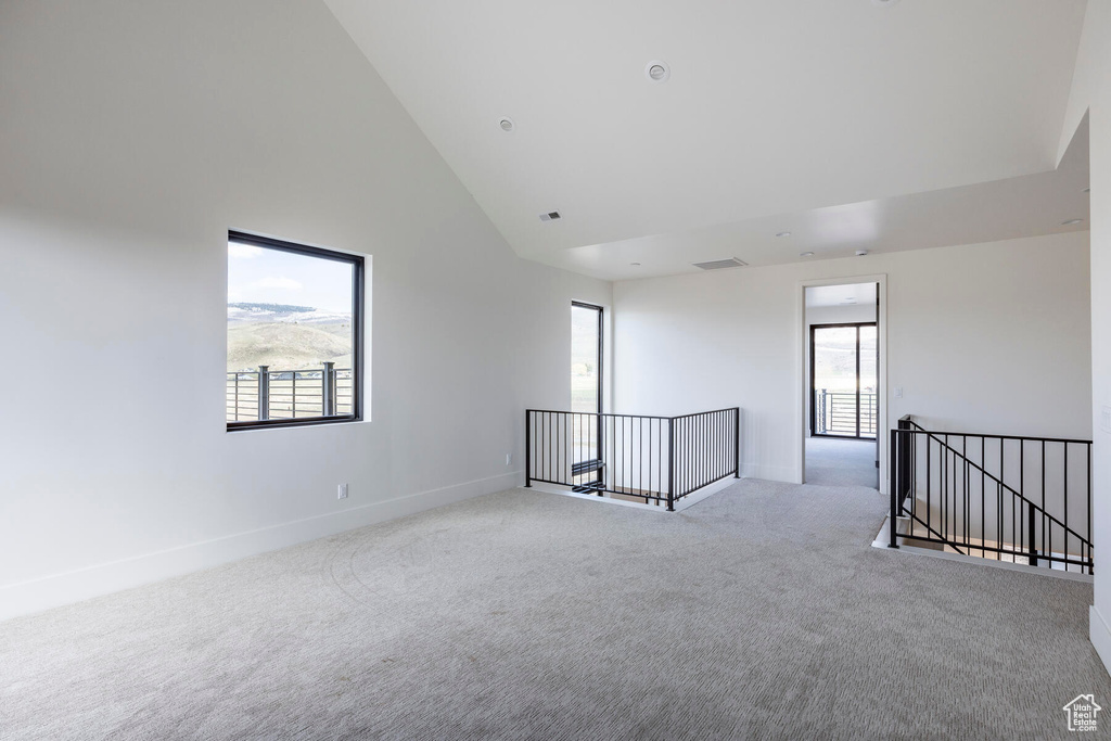 Empty room featuring high vaulted ceiling and light colored carpet