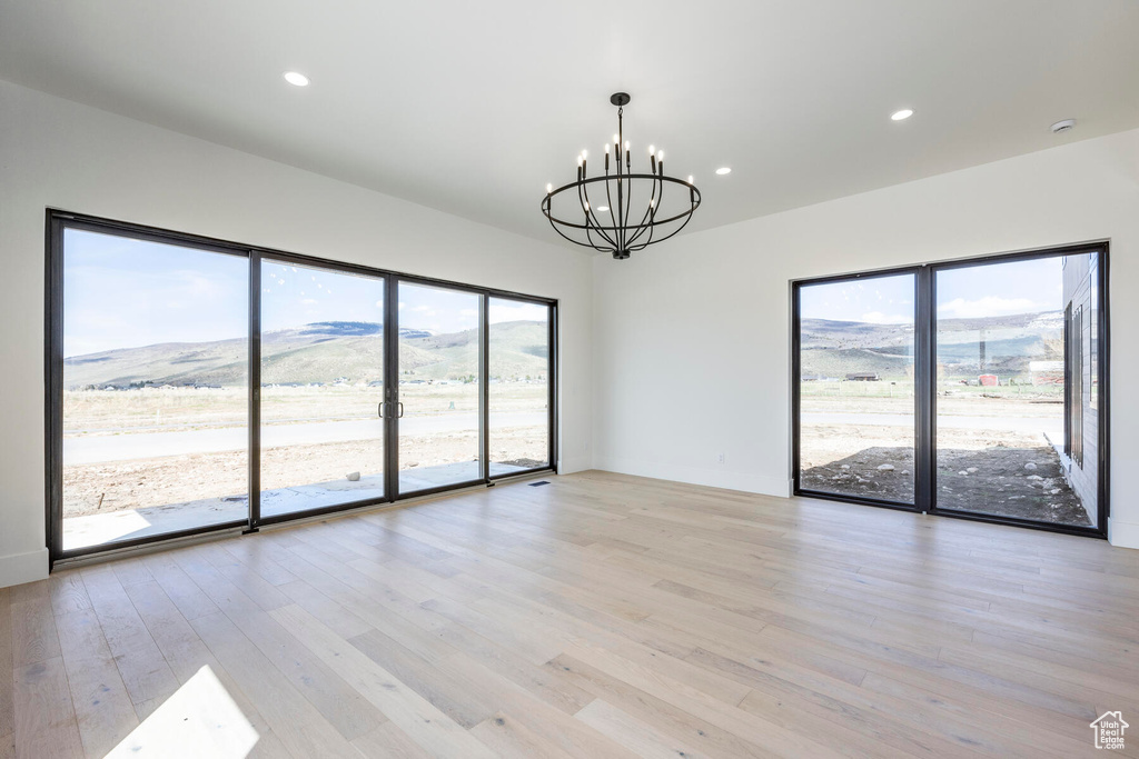 Empty room featuring an inviting chandelier, a mountain view, and light wood-type flooring