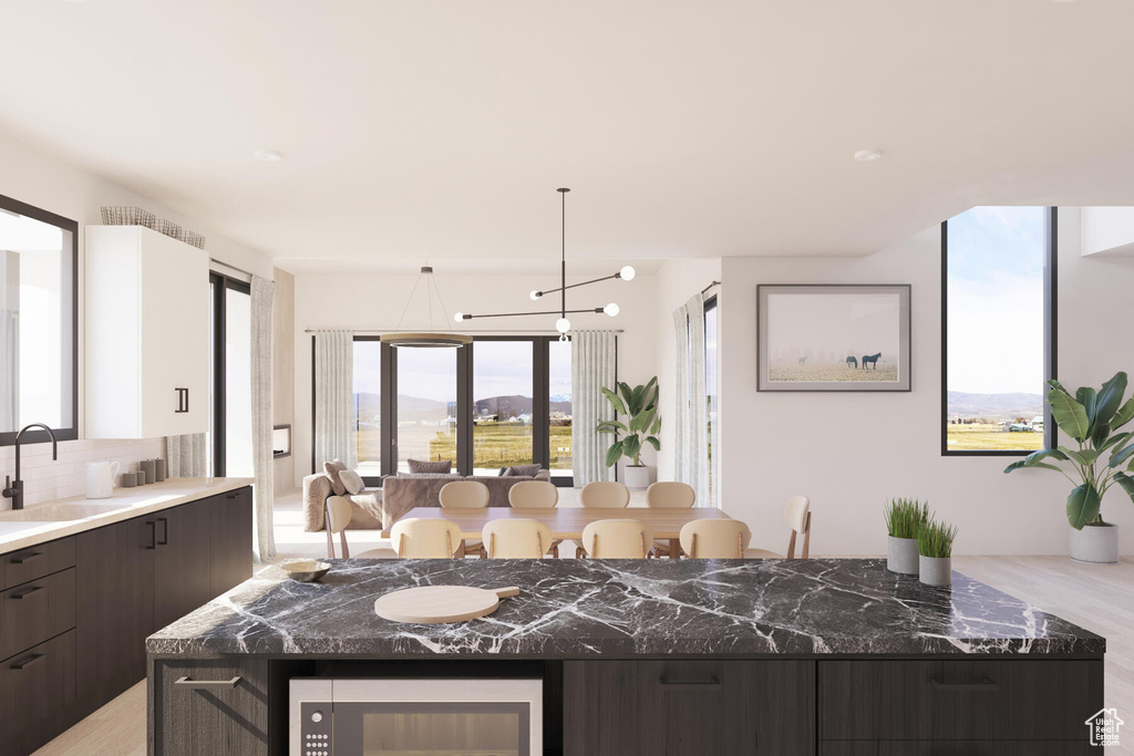 Kitchen featuring tasteful backsplash, a mountain view, light wood-type flooring, dark brown cabinetry, and a center island