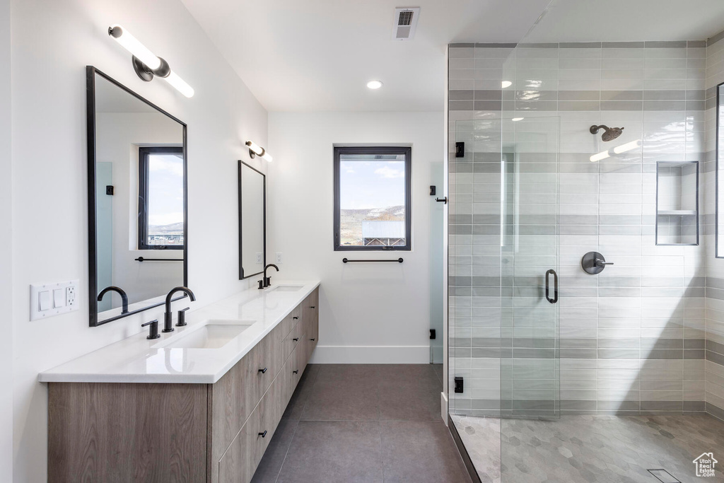 Bathroom with a shower with shower door, vanity, and tile patterned flooring