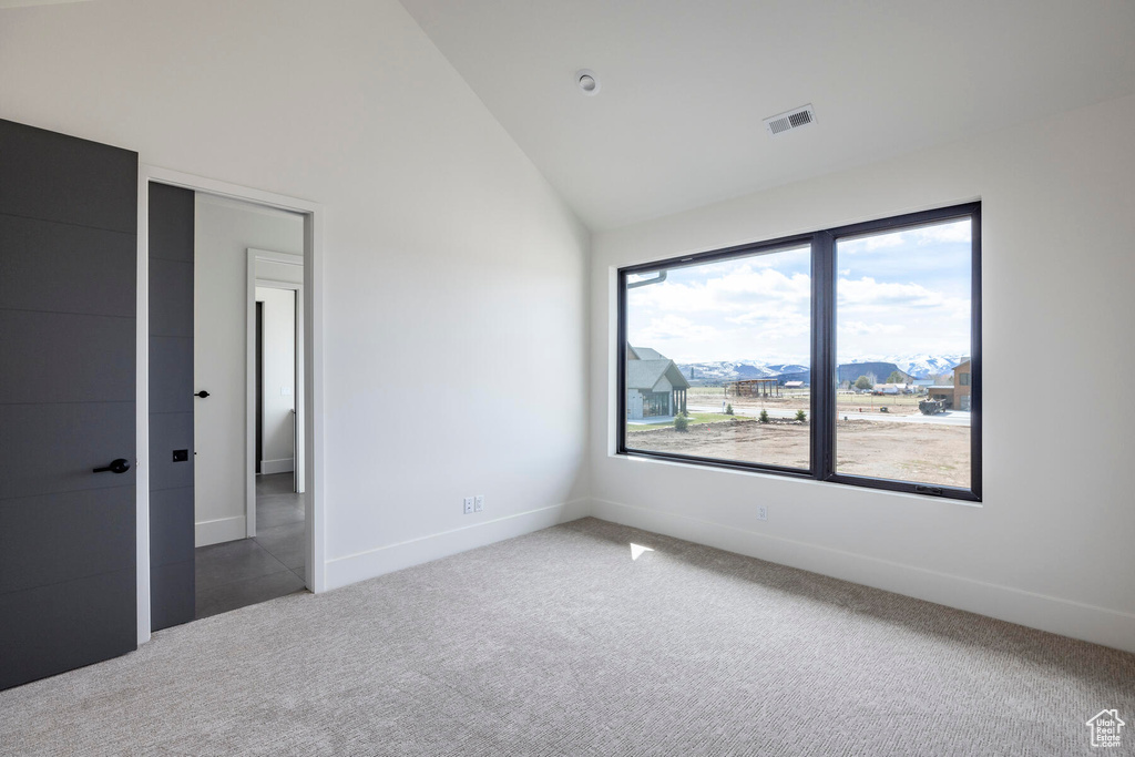 Unfurnished bedroom with a mountain view, carpet, lofted ceiling, and multiple windows