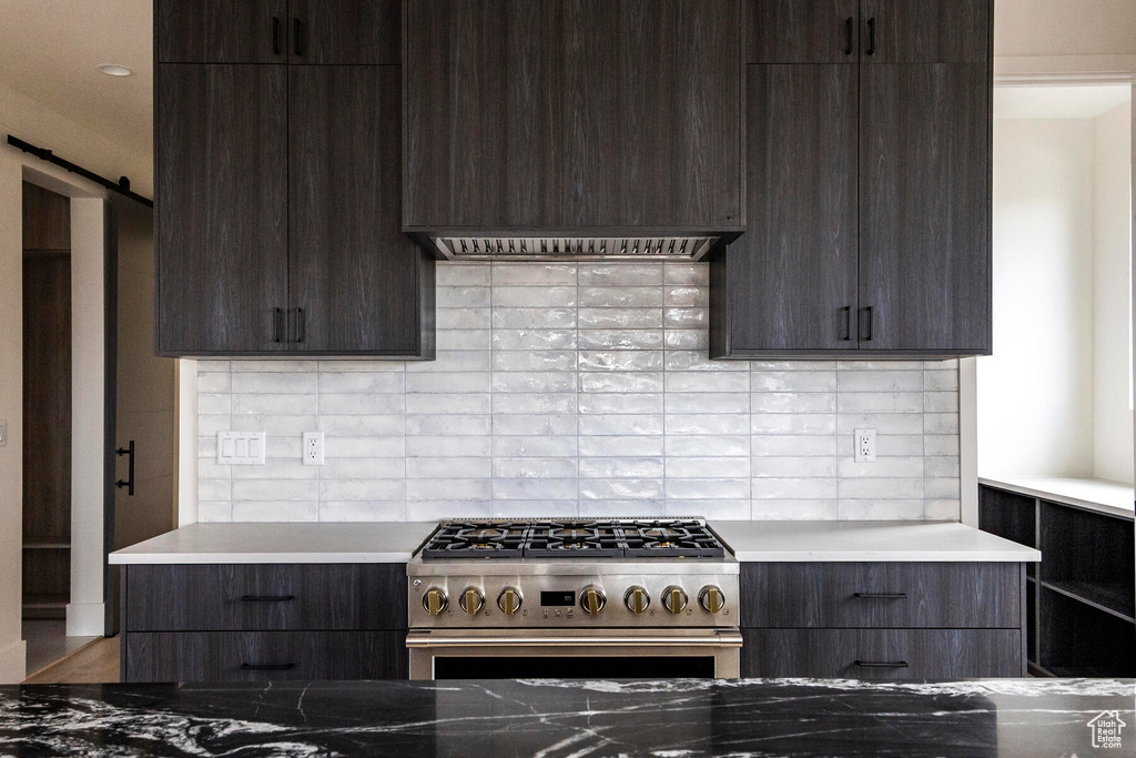 Kitchen featuring stainless steel range, a barn door, tasteful backsplash, and hardwood / wood-style floors