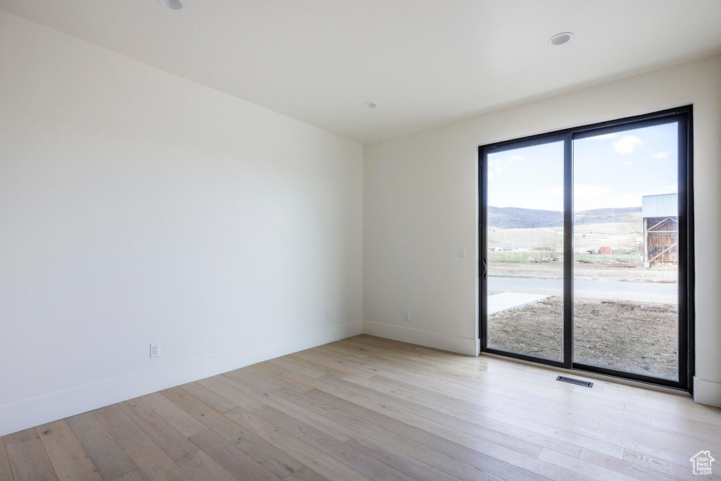 Spare room with a mountain view and light wood-type flooring