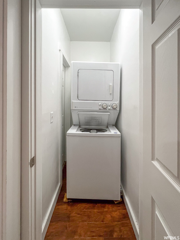 Laundry area with dark wood-type flooring and stacked washer and clothes dryer
