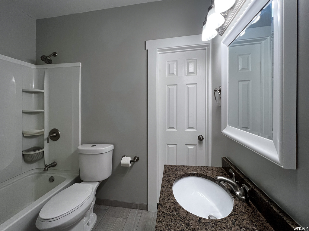 Full bathroom with bathtub / shower combination, large vanity, toilet, and tile floors