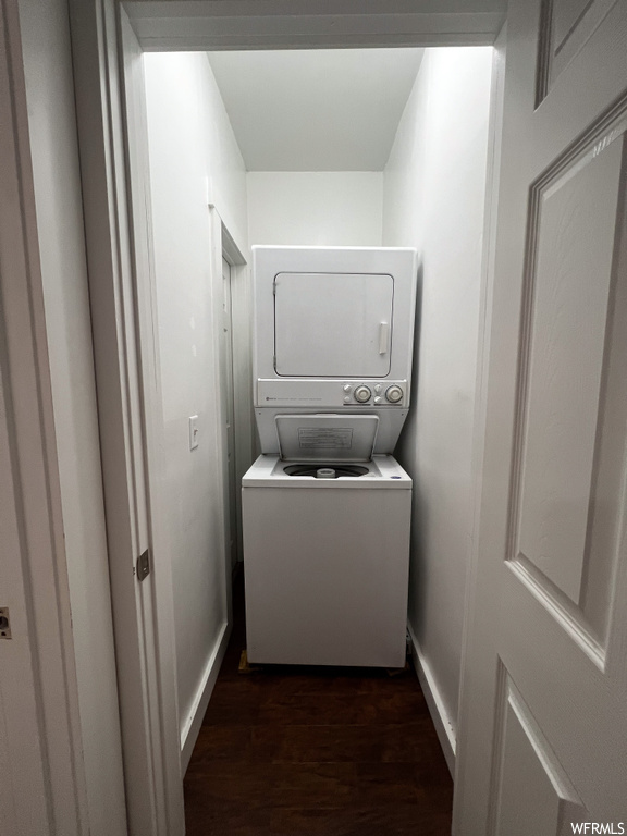 Laundry area featuring stacked washer / dryer and dark wood-type flooring