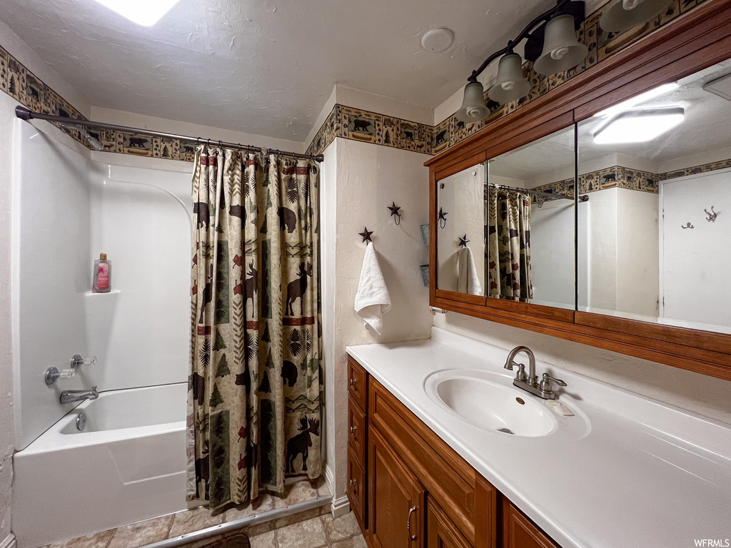 Bathroom with tile flooring, shower / bath combo with shower curtain, and vanity with extensive cabinet space