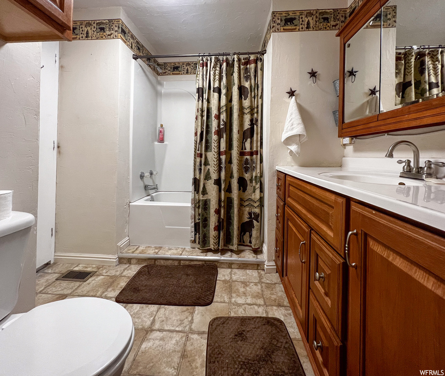 Full bathroom with tile flooring, toilet, vanity, and shower / bath combo with shower curtain
