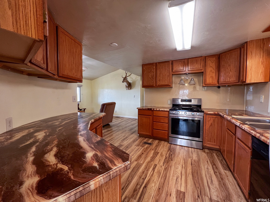 Kitchen with gas range, sink, dishwasher, and light hardwood / wood-style flooring