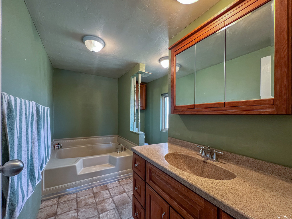 Bathroom featuring tile floors, a washtub, and oversized vanity
