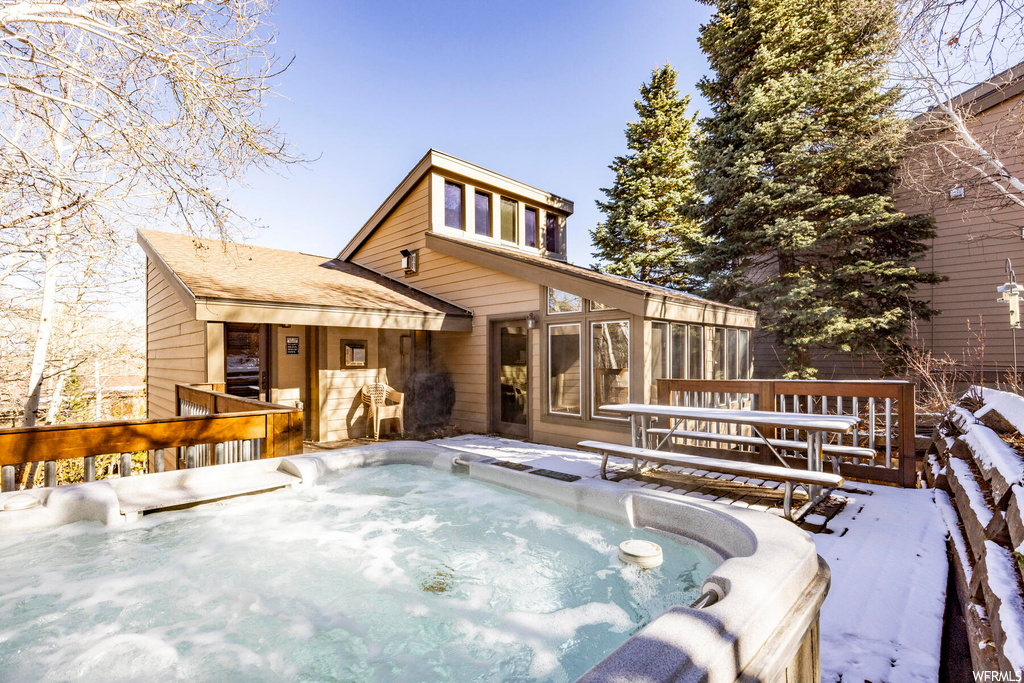 Snow covered rear of property featuring a hot tub