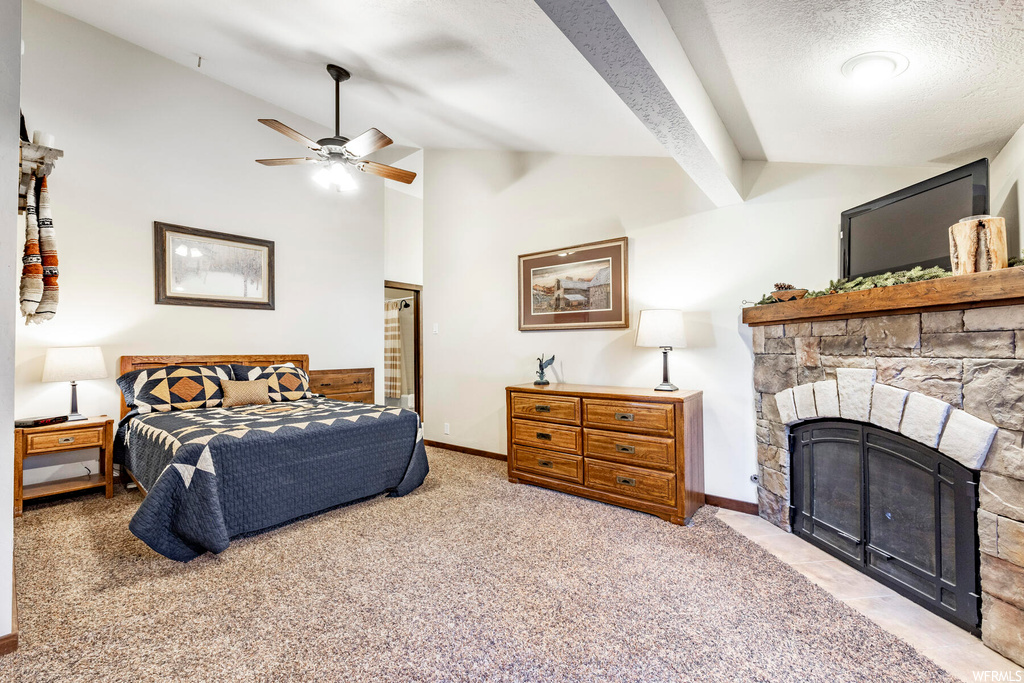 Carpeted bedroom featuring a textured ceiling, a fireplace, vaulted ceiling, and ceiling fan