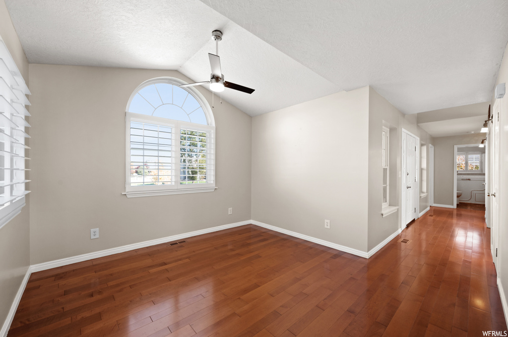 Unfurnished room with vaulted ceiling, ceiling fan, dark hardwood / wood-style flooring, and a textured ceiling
